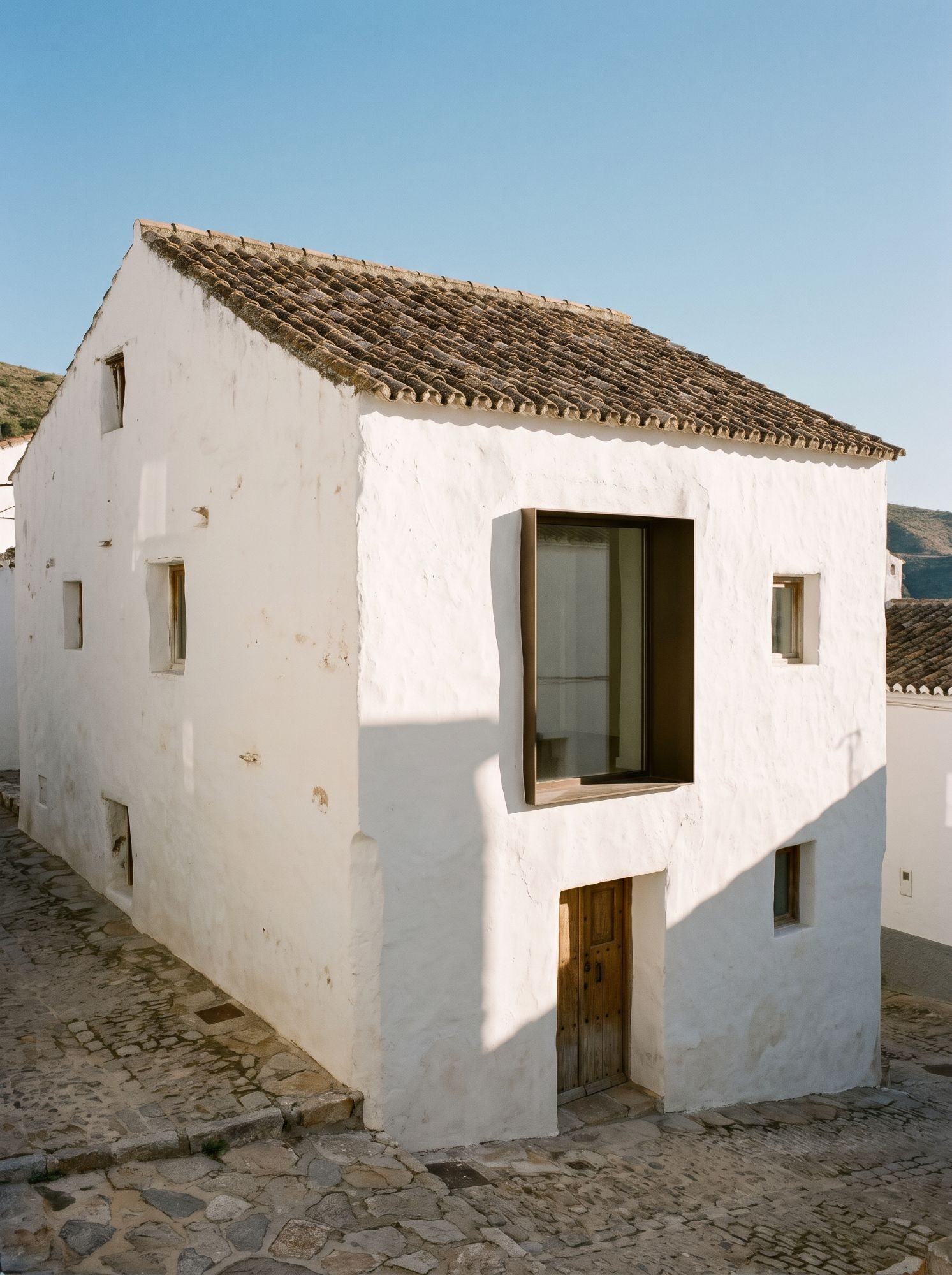 Casa encalada de un pueblo blanco con un gran hueco nuevo de bronce